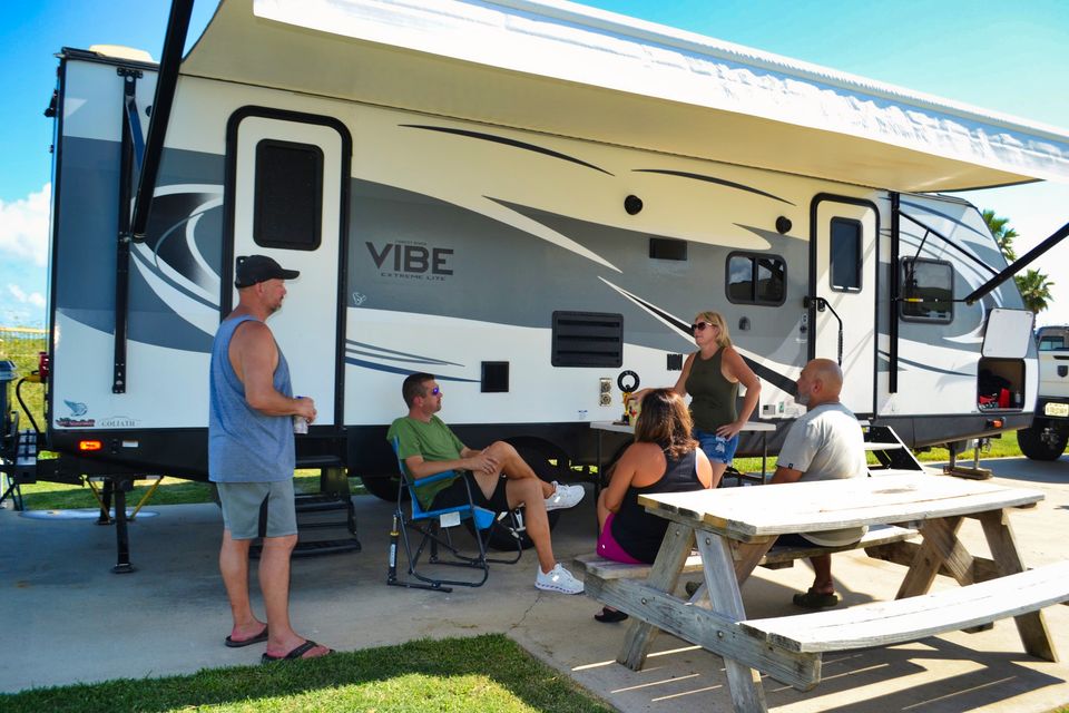 Guests gathered at a picnic table beside their travel trailer on a Sandpiper site