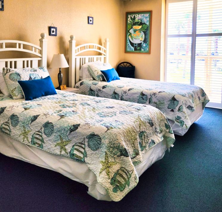A guest room with two double beds and a window to the palms